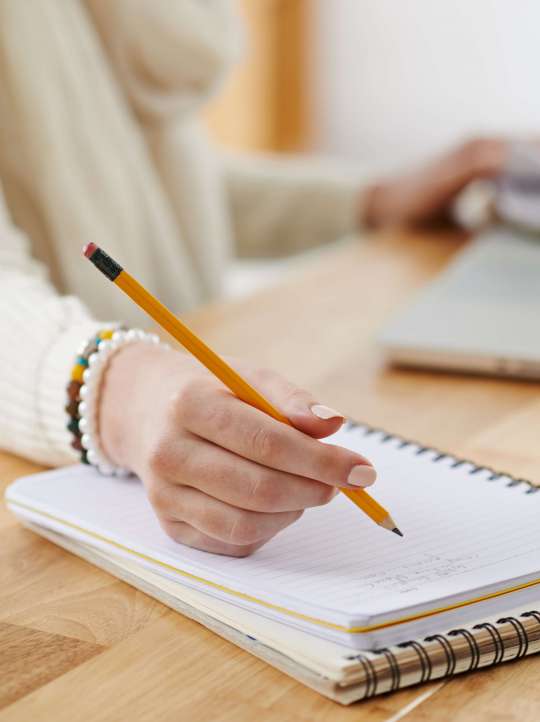 Planning work Close-up image of female office worker writing plans in notepad, selective focus